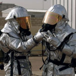 Firefighters wearing respirators on asbestos disposal site.